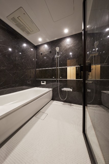 石目調のパネルとガラスドアで開放感溢れるホテルライクな浴室へ