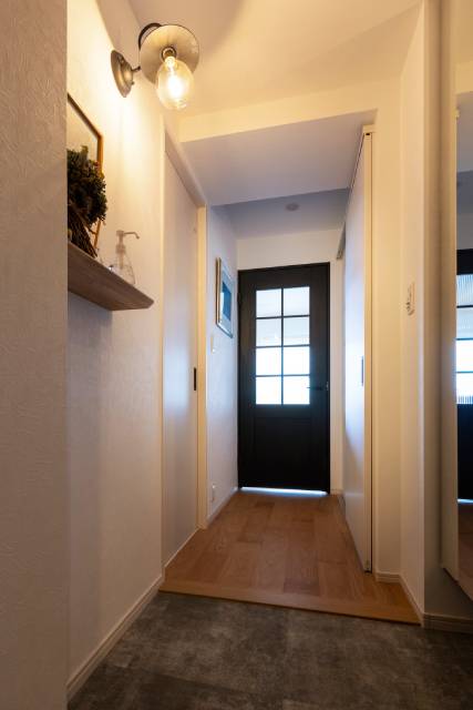 ブラケットライトが優しく照らす飾り棚が印象的なエントランス